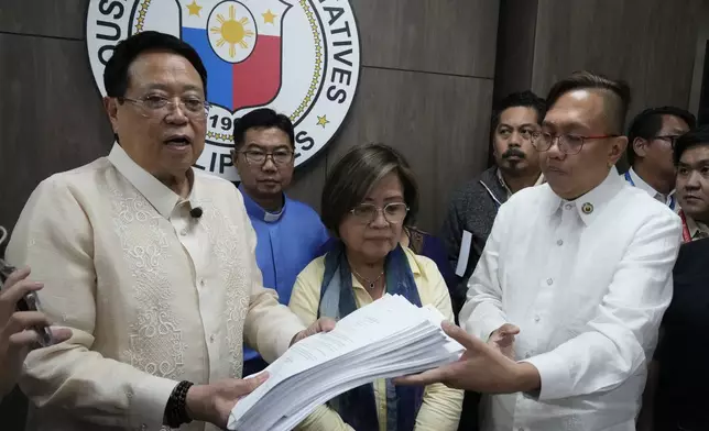 House Secretary General, Reginald Velasco, left, receives an impeachment complaint filed Monday, Dec. 2, 2024 against Philippine Vice President Sara Duterte by several prominent opponents and activists, including former Senator Leila de Lima, center, and Akbayan Partylist representative Perci Cendana, right, at the House of Representatives in Quezon City, Philippines. (AP Photo/Aaron Favila)