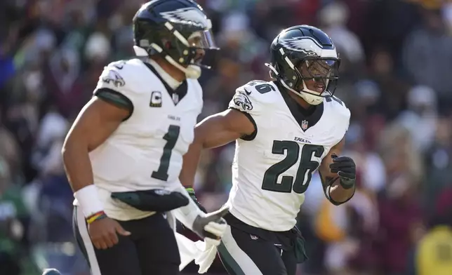 Philadelphia Eagles running back Saquon Barkley (26) celebrating his touchdown with his teammate Philadelphia Eagles quarterback Jalen Hurts (1) during the first half of an NFL football game against the Washington Commanders, Sunday, Dec. 22, 2024, in Landover, Md. (AP Photo/Stephanie Scarbrough)