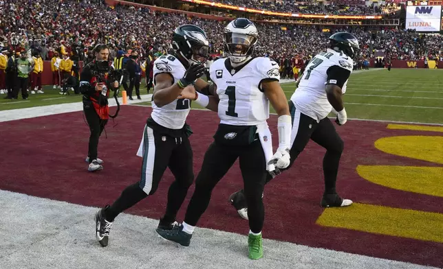 Philadelphia Eagles running back Saquon Barkley (26) celebrating his touchdown with teammate Philadelphia Eagles quarterback Jalen Hurts (1) during the first half of an NFL football game against the Washington Commanders, Sunday, Dec. 22, 2024, in Landover, Md. (AP Photo/Nick Wass)