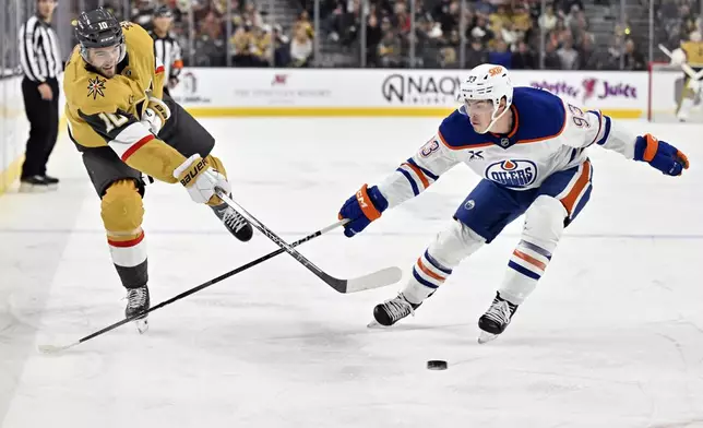 Vegas Golden Knights center Nicolas Roy passes the puck against Edmonton Oilers center Ryan Nugent-Hopkins during the second period of an NHL hockey game, Tuesday, Dec. 3, 2024, in Las Vegas. (AP Photo/David Becker)