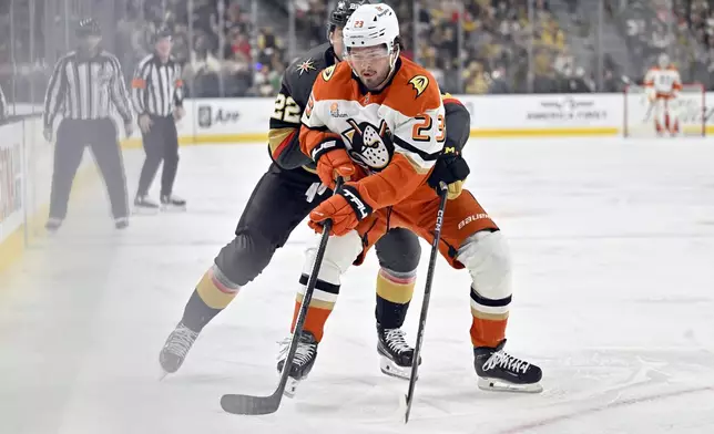 Anaheim Ducks center Mason McTavish (23) handles the puck against Vegas Golden Knights right wing Cole Schwindt (22) during the first period of an NHL hockey game Monday, Dec. 23, 2024, in Las Vegas. (AP Photo/David Becker)