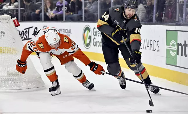 Vegas Golden Knights defenseman Nicolas Hague (14) skates with the puck against Anaheim Ducks right wing Brett Leason (20) during the first period of an NHL hockey game Monday, Dec. 23, 2024, in Las Vegas. (AP Photo/David Becker)