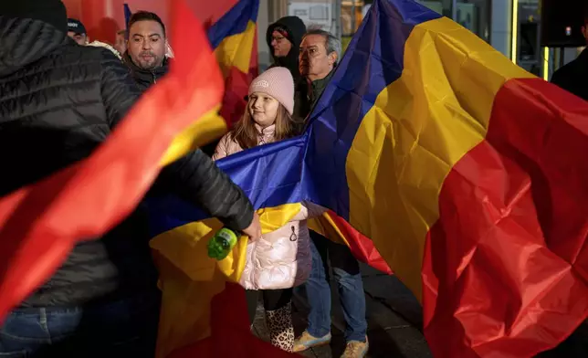 A child sits between Romanian flags before a speach by George Simion, leader of the Alliance for the Unity of Romanians (AUR) after polls closed during the country's parliamentary elections, in Bucharest, Romania, Sunday, Dec. 1, 2024. (AP Photo/Andreea Alexandru)