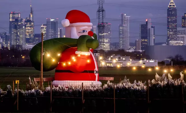 A large inflatable Santa Claus decorates the stall of a Christmas tree dealer in the outskirts of Frankfurt, Germany, Tuesday, Dec. 3, 2024. (AP Photo/Michael Probst)