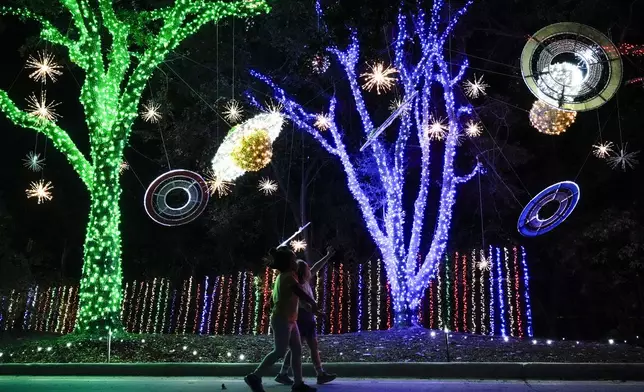 Two children react to space-themed holiday lights at Space Center Houston on Monday, Dec. 9, 2024, in Houston. (AP Photo/Ashley Landis)