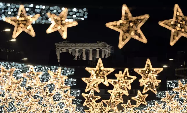 The Doric columns of the floodlit, 5th Century BC Parthenon Temple on the Acropolis appear behind strings of Christmas street lights, in Athens, Greece, Monday, Dec. 9, 2024. (AP Photo/Thanassis Stavrakis)