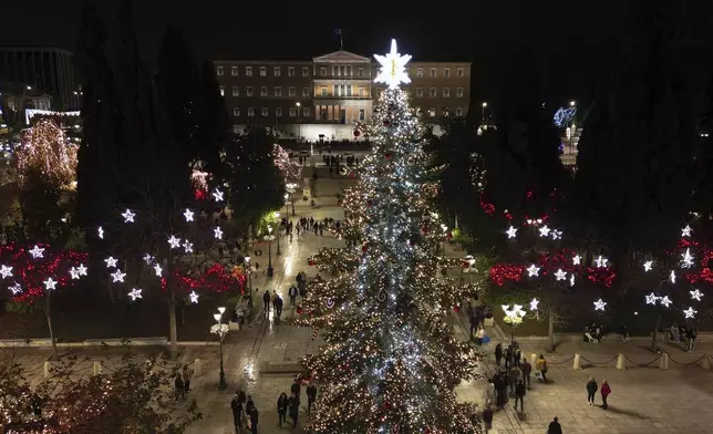 People walk at Syntagma square as the Christmas tree is illuminated in Athens, Greece, Monday, Dec. 9, 2024. (AP Photo/Thanassis Stavrakis)