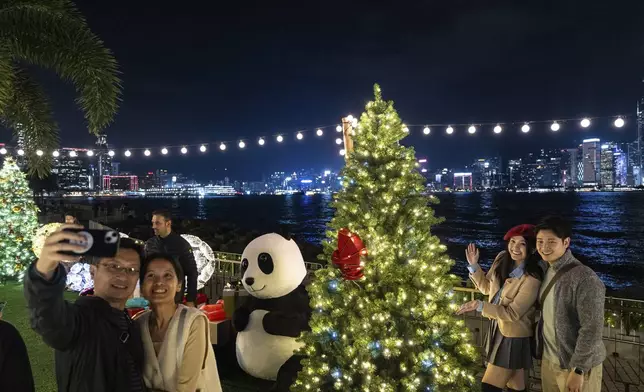 People take pictures with the Christmas tree at the waterfront of the Victoria Harbour in West Kowloon Cultural District as the city prepares for the upcoming Christmas in Hong Kong, Friday, Nov. 22, 2024. (AP Photo/Chan Long Hei)