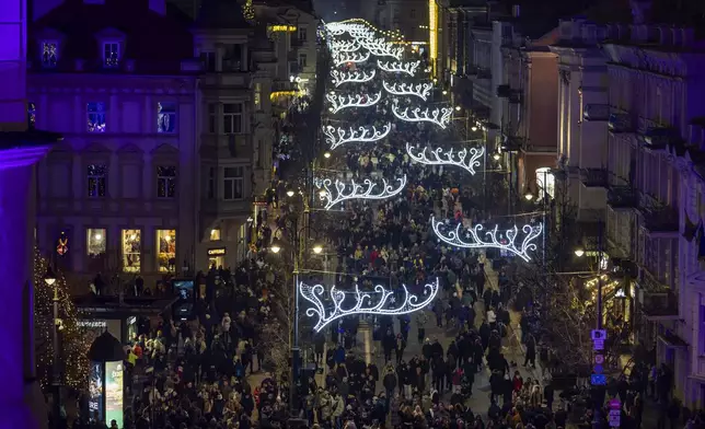 People stroll on the Christmas illuminated Gedimino Avenue during the lighting ceremony in Vilnius, Lithuania, Friday, Nov. 29, 2024. (AP Photo/Mindaugas Kulbis)