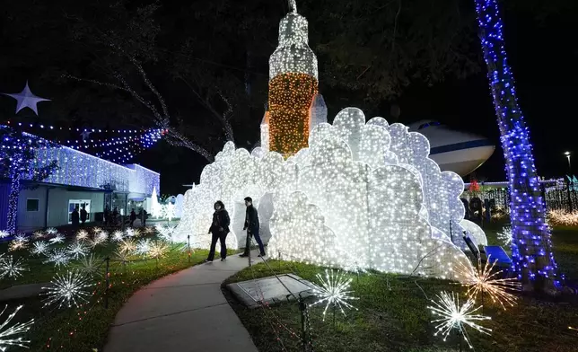 People walk among space-themed holiday lights at Space Center Houston on Monday, Dec. 9, 2024, in Houston. (AP Photo/Ashley Landis)