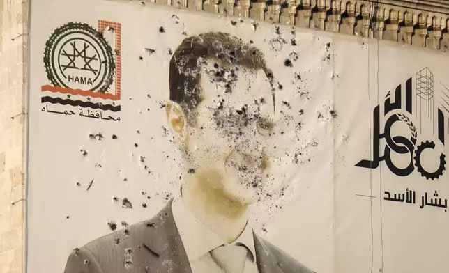 An image of Syrian President Bashar Assad, riddled with bullets, is seen on the facade of the provincial government office in the aftermath of the opposition's takeover of Hama, Syria, Friday, Dec. 6, 2024. (AP Photo/Omar Albam)