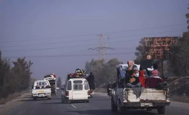 Residents leave the city carrying their belongings in Hama, Syria, Friday Dec. 6, 2024.(AP Photo/Omar Albam)
