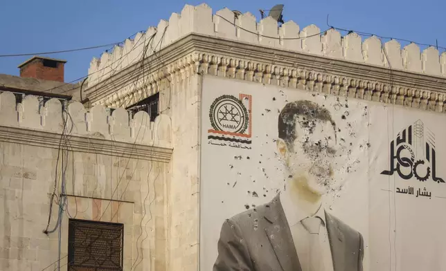 An image of Syrian President Bashar Assad, riddled with bullets, is seen on the facade of the provincial government office in the aftermath of the opposition's takeover of Hama, Syria, Friday, Dec. 6, 2024. (AP Photo/Omar Albam)