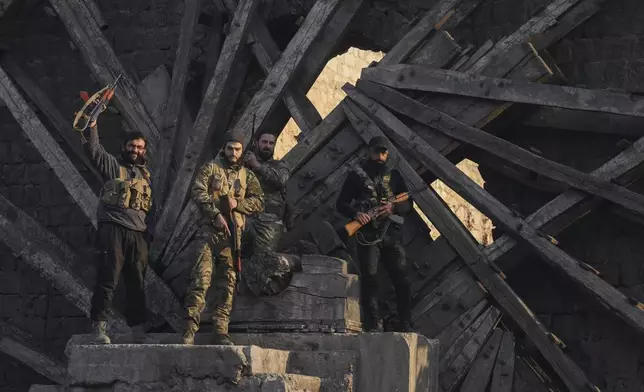 Insurgent fighters celebrate in the aftermath of the opposition's takeover of the city in downtown Hama, Syria, Friday, Dec. 6, 2024. (AP Photo/Omar Albam)