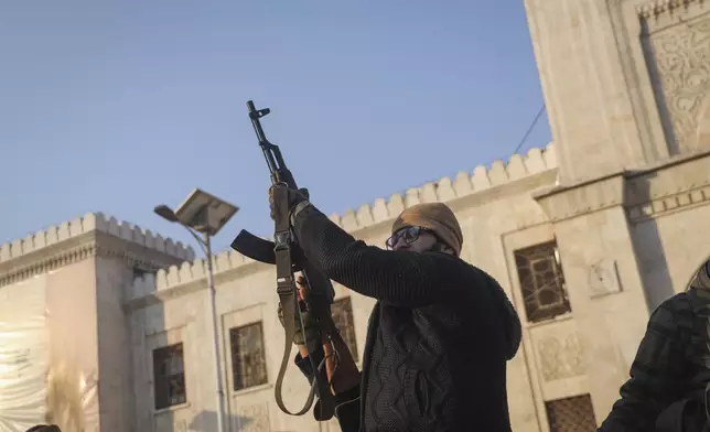 An opposition fighter fires his AK-47 in the air in celebration in Hama, Syria, Friday Dec. 6, 2024.(AP Photo/Omar Albam)