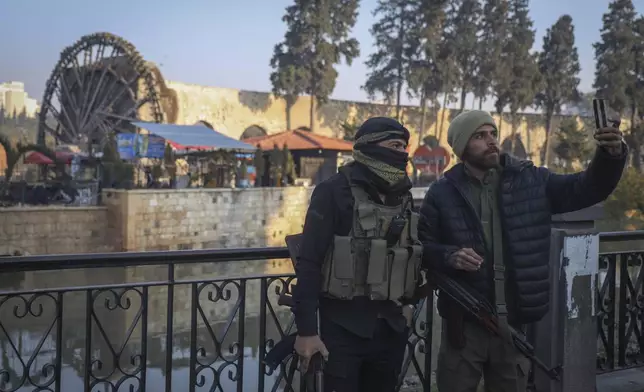 Insurgent fighters take a selfie in the aftermath of the opposition's takeover of the city in downtown Hama, Syria, Friday, Dec. 6, 2024. (AP Photo/Omar Albam)
