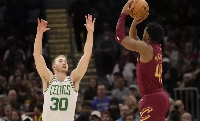 Cleveland Cavaliers guard Donovan Mitchell (45) prepares to shoot a 3-point basket over Boston Celtics forward Sam Hauser (30) in the second half of an NBA basketball game, Sunday, Dec. 1, 2024, in Cleveland. (AP Photo/Sue Ogrocki)