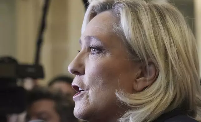 French far-right leader Marine Le Pen, center, answers reporters at the National Assembly and confirmed the National Rally party will vote against Prime Minister Michel Barnier in an upcoming no-confidence vote, Monday, Dec. 2, 2024 in Paris. (AP Photo/Michel Euler)