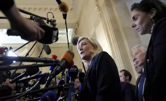 French far-right leader Marine Le Pen, center, answers reporters at the National Assembly and confirmed the National Rally party will vote against Prime Minister Michel Barnier in an upcoming no-confidence vote, Monday, Dec. 2, 2024 in Paris. (AP Photo/Michel Euler)