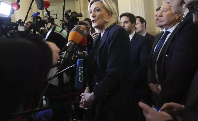 French far-right leader Marine Le Pen, center, answers reporters at the National Assembly and confirmed the National Rally party will vote against Prime Minister Michel Barnier in an upcoming no-confidence vote, Monday, Dec. 2, 2024 in Paris. (AP Photo/Michel Euler)