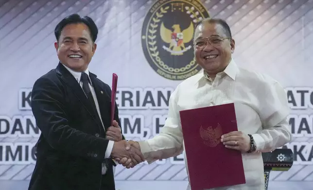 Indonesia's Coordinating Minister for Legal, Human Rights, Immigration and Correctional Affairs Yusril Ihza Mahendra, left, shakes hands with Philippine's Justice Undersecretary Raul Vasquez during the signing ceremony of a deal to send home Mary Jane Veloso, a Filipino death-row drug convict, in Jakarta, Indonesia, Friday, Dec. 6, 2024. (AP Photo/Tatan Syuflana)