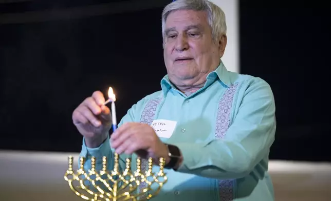 Rabbi Peter Tarlow lights a candle on a menorah during a Chicanukah event at Holocaust Museum Houston on Thursday, Dec. 19, 2024, in Houston. (AP Photo/Annie Mulligan)