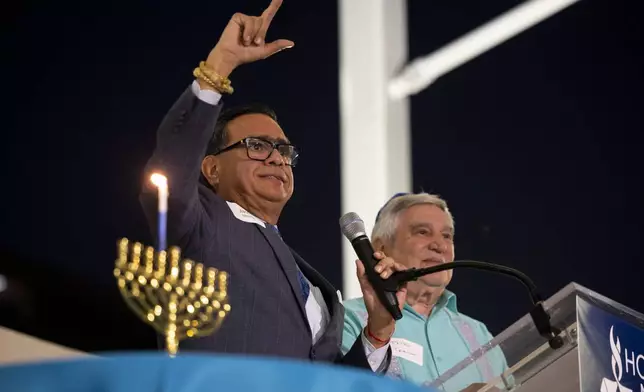 Jacob Monty joins Rabbi Peter Tarlow at the podium during a Chicanukah event at Holocaust Museum Houston on Thursday, Dec. 19, 2024, in Houston. (AP Photo/Annie Mulligan)