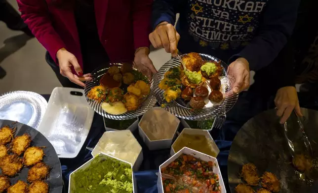 Guests add guacamole and pico de gallo to latkes during a Chicanukah event at Holocaust Museum Houston on Thursday, December 19, 2024, in Houston. (AP Photo/Annie Mulligan)