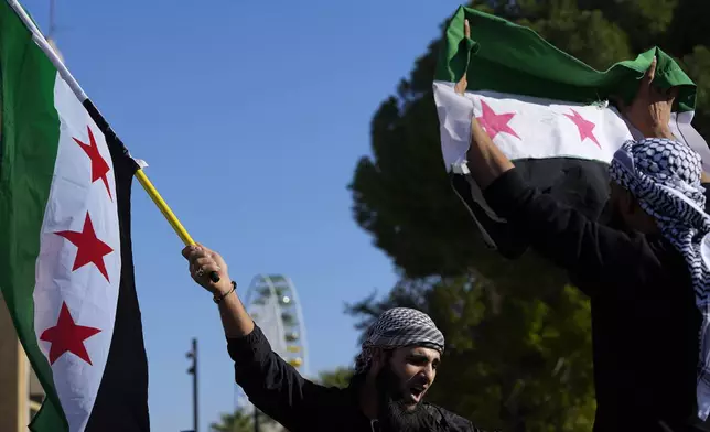 A Syrian man waves a flag during a spontaneous demonstration celebrating the fall of the Assad regime in Nicosia, Cyprus, Sunday, Dec. 8, 2024. (AP Photo/Petros Karadjias)