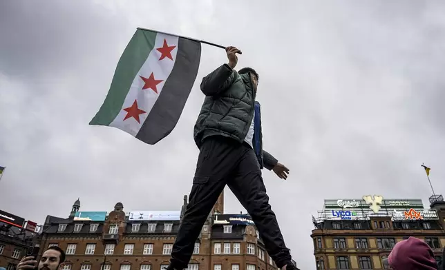 People wave Syrian opposition flags at City Hall Square in Copenhagen, Denmark, Sunday, Dec. 8, 2024. (Emil Nicolai Helms/Ritzau Scanpix via AP)