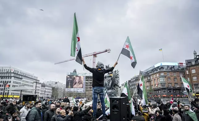 People wave Syrian opposition flags at City Hall Square in Copenhagen, Denmark, Sunday, Dec. 8, 2024. (Emil Nicolai Helms/Ritzau Scanpix via AP)