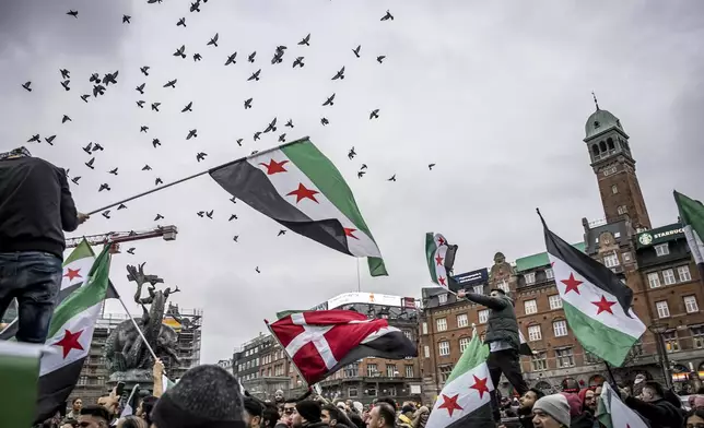 People wave Syrian opposition flags at City Hall Square in Copenhagen, Denmark, Sunday, Dec. 8, 2024. (Emil Nicolai Helms/Ritzau Scanpix via AP)