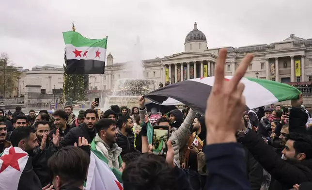 People gather to react following the fall of Syrian president Bashar Assad’s government, in Trafalgar Square, in London, Sunday, Dec. 8, 2024. (AP Photo/Alberto Pezzali)