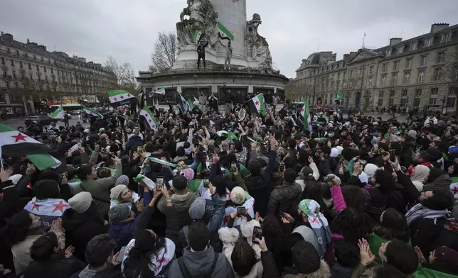 Syrians living in France gather on Republique square after the Syrian government fell early today in a stunning end to the 50-year rule of the Assad family, Sunday, Dec. 8, 2024 in Paris. (AP Photo/Aurelien Morissard)