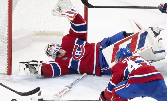 Montreal Canadiens goaltender Sam Montembeault (35) stops a shot by New York Islanders' Jean-Gabriel Pageau, not shown, as Canadiens' Jayden Struble (47) skates in to defend during the second period of an NHL hockey game in Montreal, Tuesday, Dec. 3, 2024. (Christinne Muschi/The Canadian Press via AP)