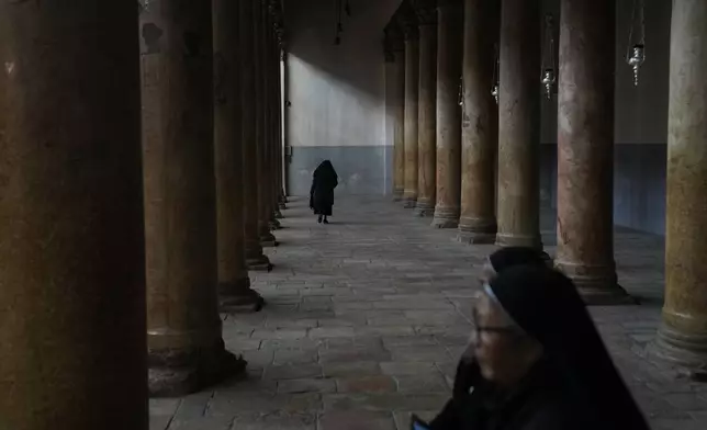 A worshipper walks through the Church of the Nativity, traditionally believed to be the birthplace of Jesus, on Christmas Eve, in the West Bank city of Bethlehem, Tuesday, Dec. 24, 2024. (AP Photo/Matias Delacroix)