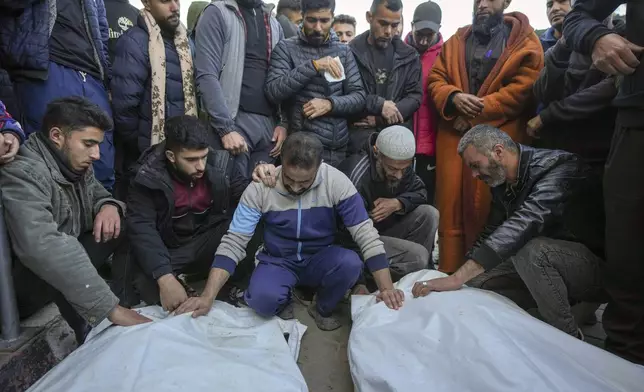 Palestinians mourn over the bodies of five policemen killed Monday by an Israeli strike in Deir al-Balah, central Gaza Strip, Tuesday Dec. 24, 2024. According to witnesses at the scene, the policemen fired shots to prevent a group of bandits blocking the road from stealing aid from a truck. The Israeli army immediately struck the policemen after that.(AP Photo/Abdel Kareem Hana)