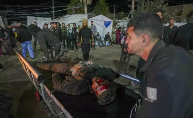 A dead man is taken into the Al-Aqsa Martyrs Hospital after a car was hit by an Israeli airstrike killing four people in Deir al-Balah, central Gaza Strip, Monday Dec. 23, 2024. (AP Photo/Abdel Kareem Hana).