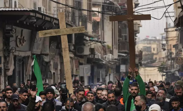 Syrian Christians hold up crosses and shout slogans in Damascus, Syria, Tuesday, Dec. 24, 2024 as they march during a protest after a Christmas tree was set on fire in Hamah city on Sunday. (AP Photo/Hussein Malla)