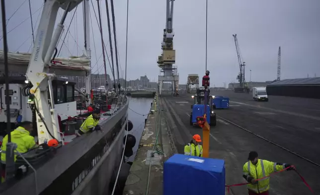 Dockers load pallets onto the sailboat 'Grain de Sail II' at the port of Saint Malo, western France, Nov. 8, 2024. (AP Photo/Thibault Camus)