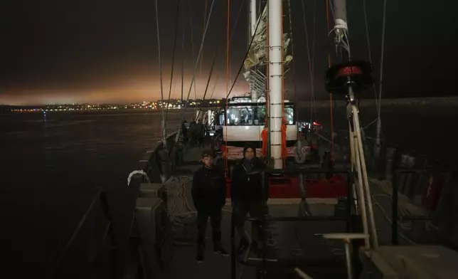 Sailors Tim Padellec, left, and Charles Mirassou stand on the deck of the sailboat 'Grain de Sail II' as he sails off Saint Malo, western France, Nov. 6, 2024. (AP Photo/Thibault Camus)