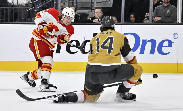 Calgary Flames center Connor Zary (47) shots against Vegas Golden Knights defenseman Nicolas Hague (14) during the first period of an NHL hockey game Sunday, Dec. 29, 2024, in Las Vegas. (AP Photo/David Becker)