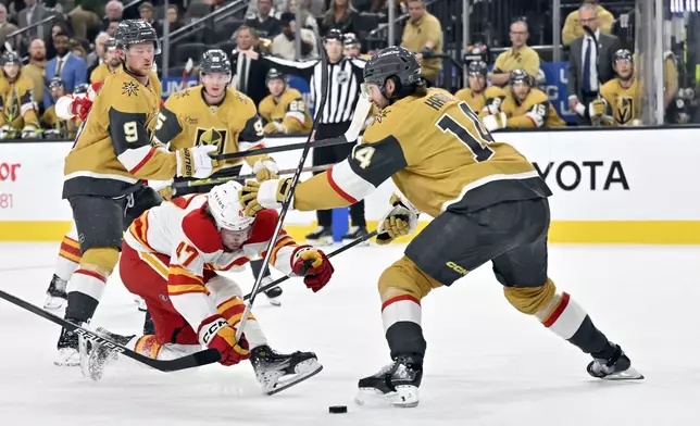 Calgary Flames center Connor Zary and Vegas Golden Knights defenseman Nicolas Hague vie for the puck during the third period of an NHL hockey game, Sunday, Dec. 29, 2024, in Las Vegas. (AP Photo/David Becker)