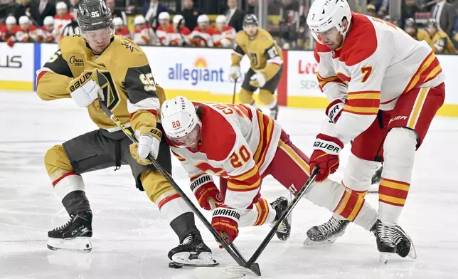 Vegas Golden Knights right wing Victor Olofsson (95) uses his skate to shield the puck from Calgary Flames center Blake Coleman (20) and defenseman Kevin Bahl (7) during the second period of an NHL hockey game Sunday, Dec. 29, 2024, in Las Vegas. (AP Photo/David Becker)