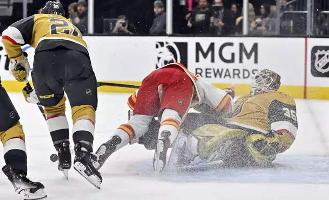 Calgary Flames left wing Ryan Lomberg, center, collides with Vegas Golden Knights goaltender Ilya Samsonov during the third period of an NHL hockey game, Sunday, Dec. 29, 2024, in Las Vegas. Lomberg was called for interference. (AP Photo/David Becker)