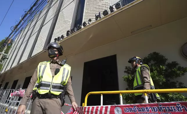 Policemen stand guard after a hotel fire in Bangkok, Thailand, Monday, Dec. 30, 2024. (AP Photo/Sakchai Lalit)