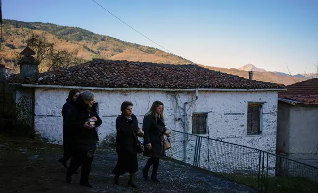 Locals leave the church after a liturgy in Fourna village, central Greece, Tuesday, Nov. 26, 2024. (AP Photo/Thanassis Stavrakis)