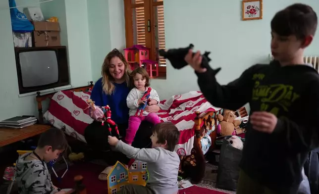 Vassiliki Emmanouil, mother of six who relocated to Fourna village a few months prior, holds her daughter Ekaterini as she plays with her children, from left, Georgios, Pavlos and Loukas at their temporary home in Fourna village, central Greece, Tuesday, Nov. 26, 2024. (AP Photo/Thanassis Stavrakis)