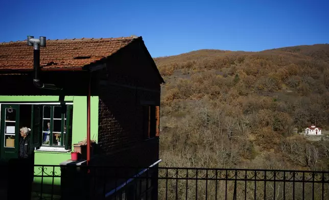 A woman stands outside her shop in Fourna village, central Greece, Monday, Nov. 25, 2024. (AP Photo/Thanassis Stavrakis)