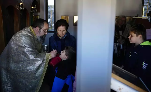 Rev. Constantine Dousikos gives communion to children at the Orthodox church of Agios Stylianos in Fourna village, central Greece, Tuesday, Nov. 26, 2024. (AP Photo/Thanassis Stavrakis)